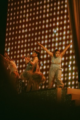 Singer and dancers in front of a glowing dotted screen
