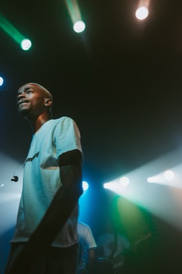 Performer on stage under teal and green concert lights