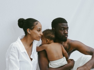 Family portrait with a sleeping baby against a white wall