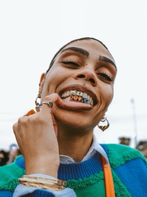 Close-up smile showing colorful grillz at a festival