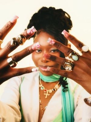 Portrait framed by hands with 3D floral nails and gold rings