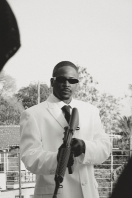 YG in a white suit on a balcony, sepia black and white